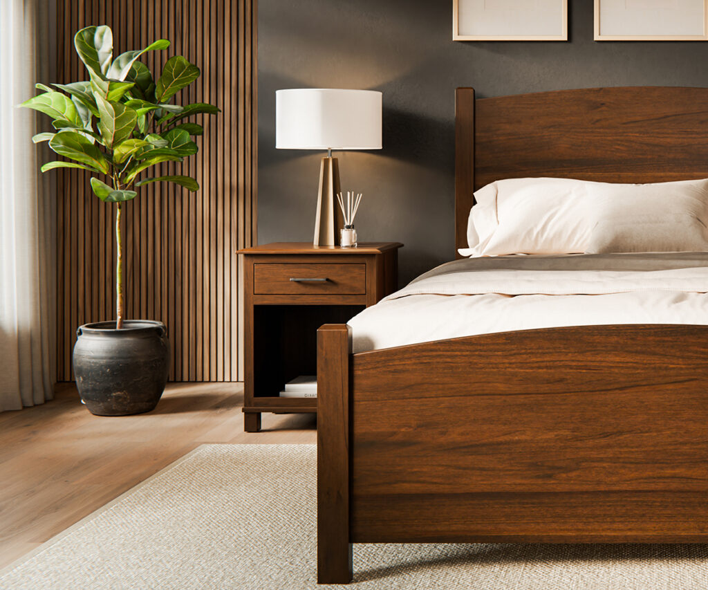A handcrafted Amish solid wood bed and matching nightstand displayed in a modern bedroom with white bedding, a table lamp and a potted plant.